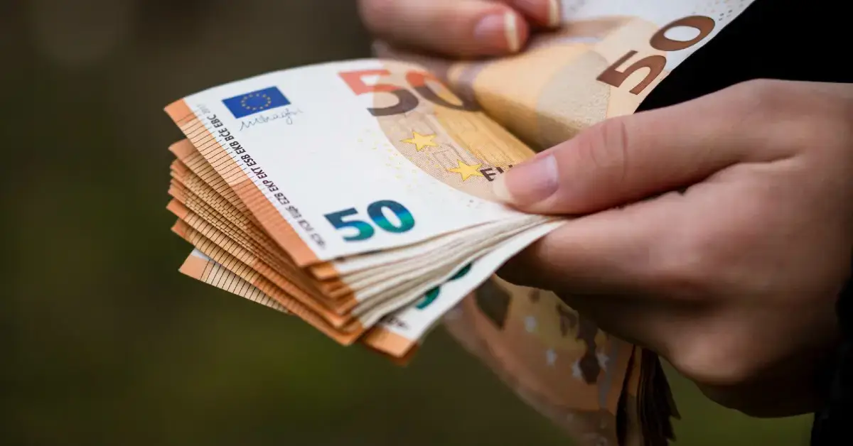 Kobieca dłoń licząca plik banknotów euro