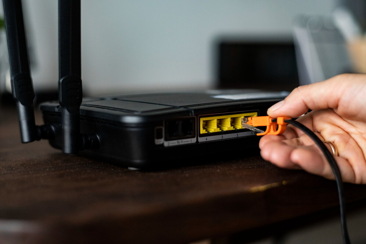 dłoń podłączająca kabel do routera od Internetu