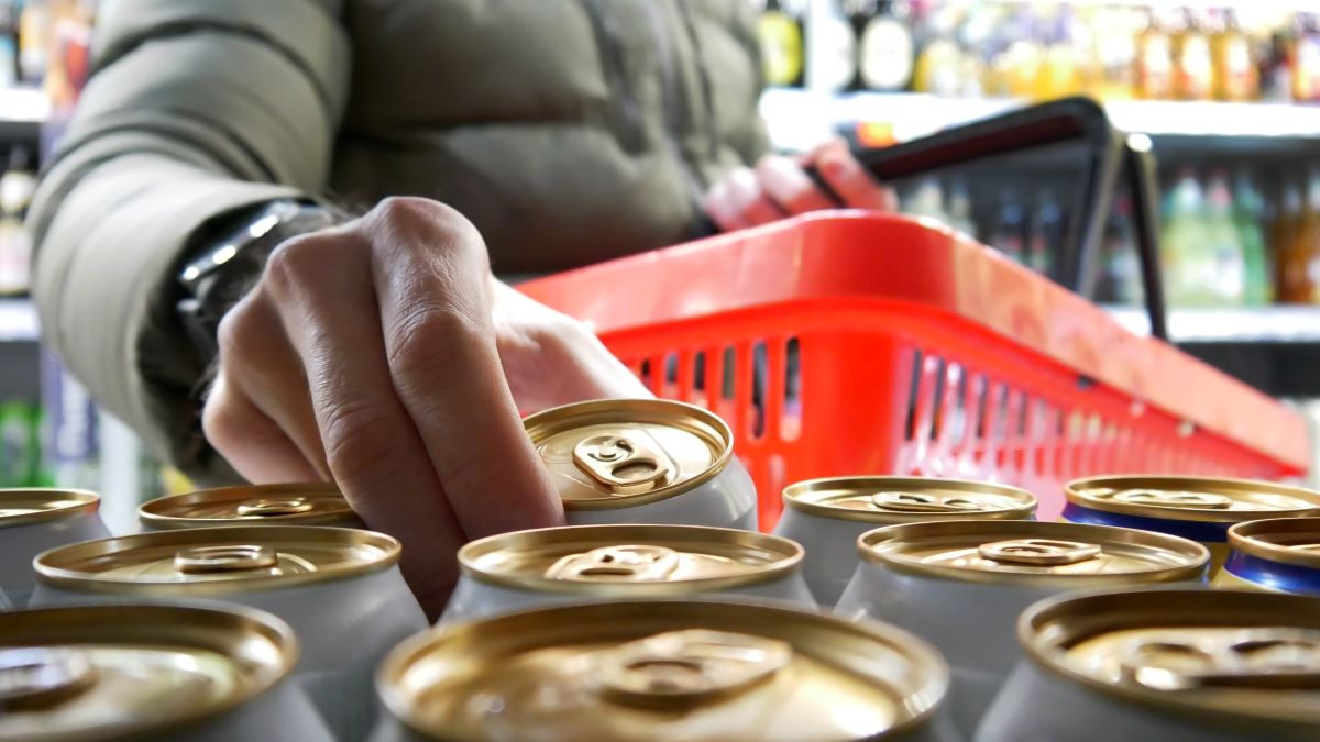 Mężczyzna sięga po puszkę w sklepie podczas zakupów.